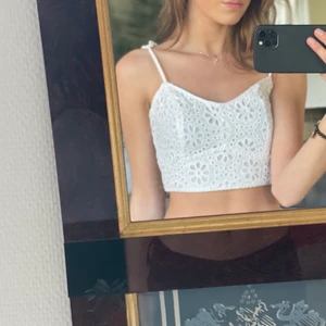 Sommartopp - En super söt vit, blommig topp. Perfekt till sommaren eller vid finare tillfällen! Jättefint mönster, resår i ryggen så den passar fler kroppar och med justerbara axelband med jättefina tofsar🥰