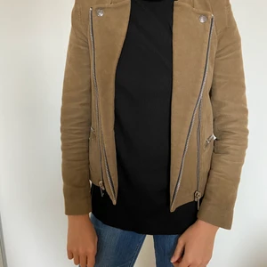 Militärgrön bikerjacka - Militärgrön bikerjacka med silverdetaljer, 2 fickor, dragkedja. Mockaimitation. Använd med fint skick. Märke: Zara