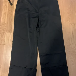 Byxor från NA-KD - Siden byxor från NA-KD, använda 1 gång, de är väldigt långa i benen och stor i storlek. Älskar byxorna och snygg passform men som sagt är de väldigt långa i benen. Jag är 1.59cm och de släpar i golvet