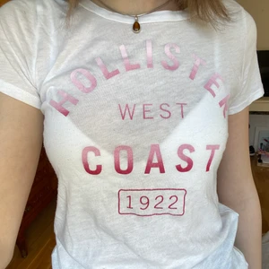 Vit t-shirt från Hollister  - Vit t-shirt från Hollister i storlek xs med rosa text på. Supermjukt tyg och verkligen jätteskön! Den är i bra skick:)