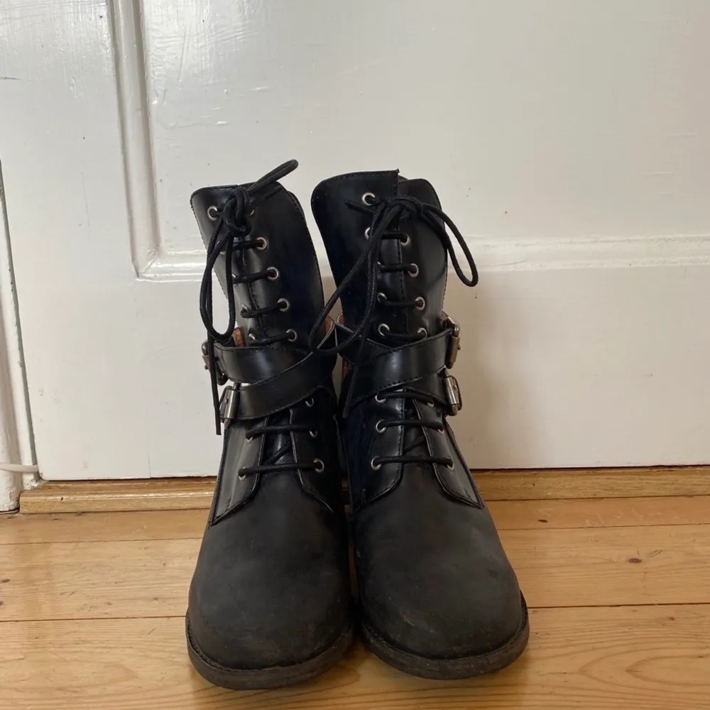 Mattsvarta boots i läder från Jeffrey Campbell med omlottspännen och hög plös med snörning, dragkedja bak. Jättesköna att gå i. Robusta sulor med mycket lite slitage, och märken på klackarnas insida då jag cyklade med dem en gång. (Se bild)  Köpte 2014 i USA och använda kanske fyra gånger sedan dess så dags att de får en ny ägare! Amerikansk storlek 7.. Skor.