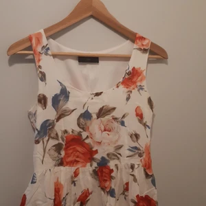 Blommig Klänning - Klänning med lite volym i kjolen, dragkedja i sidan. 78 cm lång från axeln.