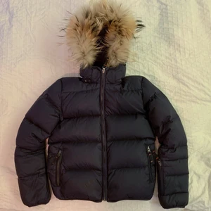 Dunjacka från VER de TERRE - Säljer min dunjacka jag använde när jag var 15 år (använd endast en säsong). Köpt i januari 2017 på NK barn från märket ”VER de TERRE” för 2500kr. Väldigt bra skick, inga fläckar, inget trasigt. Äkta päls på luvan, den är även avtagbar om så skulle viljas. Färgen är marinblå. Storleken är 10år, själv använde jag den när jag var ca 160 lång och kunde använda stl 146 i barnstorlekar