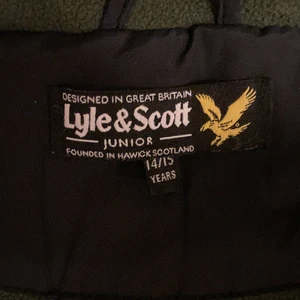 Lyle & Scott junior vinterjacka - En varm och skön Lyle & Scott vinterjacka som är mycket litet använd. Storlek: 14-15 år. Färg: svart med grönt foder. Köpt på kidsbrandstore.
