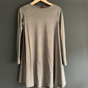 Grå klänning i trikåmaterial - Nästan oanvänd klänning i stretchigt trikåmaterial. Utsväng kortare modell. Märket är Missi och är i storlek s/m. Köparen står för frakt