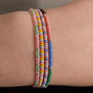Fyra Multifärgade armband med många rosa pärlor.  Det är stretch på tråden och passar de flesta