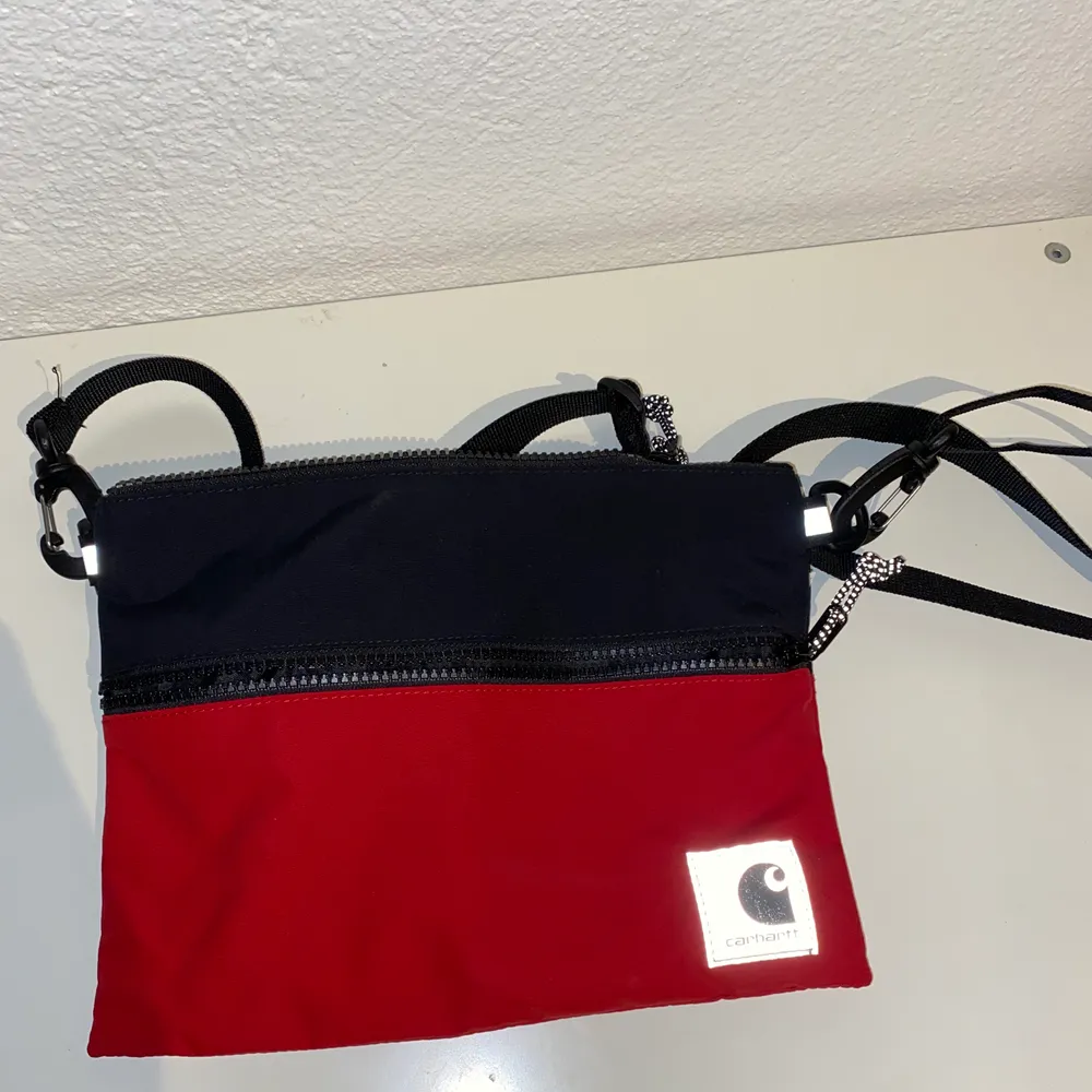 Hej! Säljer en carhartt dexter strap bag i färgen röd och svart, väskan har aldrig kommit till använding så den är som ny. Om du har någon frågar så är det bara att fråga på:) . Väskor.