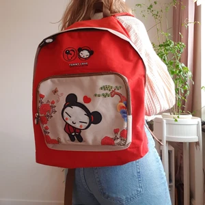 Officiell Pucca ryggsäck från puccaclub.com - Jättesöt rymlig ryggsäck med Pucca🌸 Väldigt lent och fint tyg. Har små små fläckar undertill (se bild 3, höger), men jag har inte testat att ta bort dem. Även lite slitage mellan remmarna (se bild 3, vänster). I övrigt är väskan i väldigt bra skick! Samfraktar gärna!