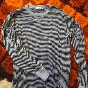 Långärmad tröja - Stickad långärmad tröja med grå och svarta ränder. Storlek S från Lager 157. Aldrig använd så är i nyskick! Går att mötas upp i Hagfors eller så skickas den med posten där köparen står för frakten!