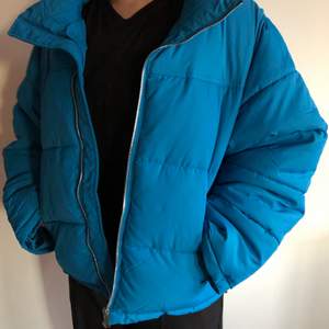 Helt ny oanvänd puffer jacket. Jackan är i storleken XL men passar även mig (första bilden) som vanligtvis bär S eller M, så funkar till alla blir bara mer eller mindre oversized. Finns 2 fickor med dragkedja, ingen luva och silverdetaljer. Har även samma fina blåa färg på insidan och går att spänna åt i midjan