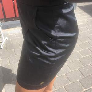 En svart kjol i ett lite glansigt material. Den är i bra skick och är i storlek 36. Kjolen har också en väldigt fin passform. Frakten går även att dra ner priset på vid intresse 