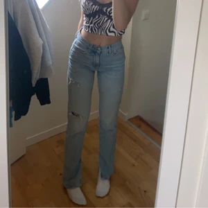 Blåa jeans med slits och slitningar  - Så fina mid waist jeans med asfina detaljer har fått en blek fläck orsakat av klorin på baksida (se bild 3) 