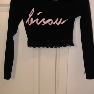 Svart crop top - Svart långärmad crop top med rosa test på och spets nertill 