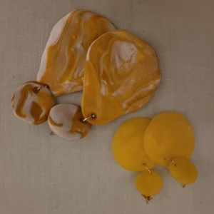 Abstrakta örhängen - Två par handgjorda örhängen i lera. Inköpta för cirka två är sedan och används inte längre men är jättefina. Stark gul färg på båda. Felfritt skick men då de är handgjorda så är de inte perfekta i kanterna. Enligt mig adderar det till det fina abstrakta utseendet.