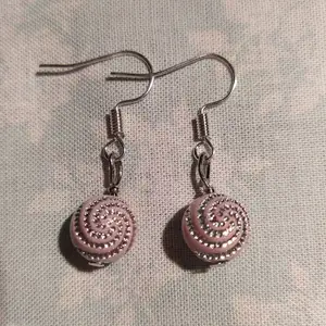 Ett par hemmagjorda örhängen med rosa pärlor och silvermönster. Krokarna är nickelfria, oanvända.