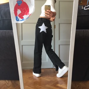 Jeans med stjärnor  - Ett par svarta jeans med vita sömar som är från weekday. Jag har själv sytt på två ljusblå stjärnor där bak. Fint skick. Högmidjade men på mig passar det lågmidjat. Jag är 168!! Har själv klippt två slitsar, på innerbenet. 
