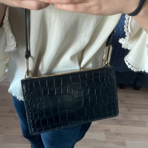 Snakeprint väska från The Other Stories - Supersnygg och Trendig väska från The Other Stories. Glansigt snakeprint med guld detaljer, väskan finns inte till salu i butik längre. Äkta läder på utsidan och insidan är 100% bomull. Köpt för 1400 kr. Mycket bra skick och längd på bandet går att reglera, Se bilder! (Frakt medkommer utifrån pris)