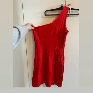 Röd fin klänning i one-shouldermodell. Knappt använd. Köparen står för frakt. 
