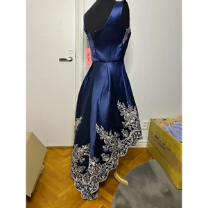 Asymmetriska Balklänning marinblå - Asymmetriska balklänning storlek : M, köpte på Zalando, oanvänt, lappen finns kvar.    Färg : marinblå med grå glittriga detaljer   Anledning till försäljning : beställde den förra året, den var tänkt att ha till balen 2021 men hade uppehåll pga graviditet kan jag inte längre ha den. Priset som jag köpte låg 1000+ kr   