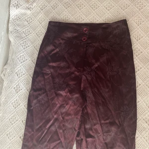 Bootcut byxor från Pantalon Tomy  - Glansiga byxor i fint skick. I ett blommig mönster. Katt i hemmet.  Kan mötas upp i Uddevalla centrum om ej så står köparen för frakten. 