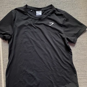 ESSENTIAL TRAINING TEE GYMSHARK - Helt vanlig svart träningströja ifrån gymshark i strl.L. Sitter tight även på M. Säljer pga har flera likadana. Inga märken eller slitage, typ som ny. 