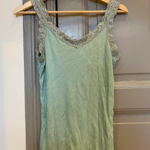 Grönt linne med spets  - Trendigt rubbat linne med spets som passar XS till M beroende på hur tajt en vill ha det! Själv är jag s och det är inte så tajt. ( frakt tillkommer!) 