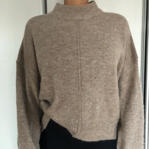 Stickad tröja med halvpolokrage - Beige stickad tröja från Gina Tricots premium collection. Markerad söm i mitten av tröjan och halvpolo upptill. Använd ett fåtal gånger, superfint skick. Har vanligtvis S/M på överdelar men köpte denna i L för en mer oversized känsla. Innehåller bl a akryl, polyester och alpacka. Finns vid Älvsjö torg att hämta. Kan även skickas via Postnord mot en fraktkostnad. 