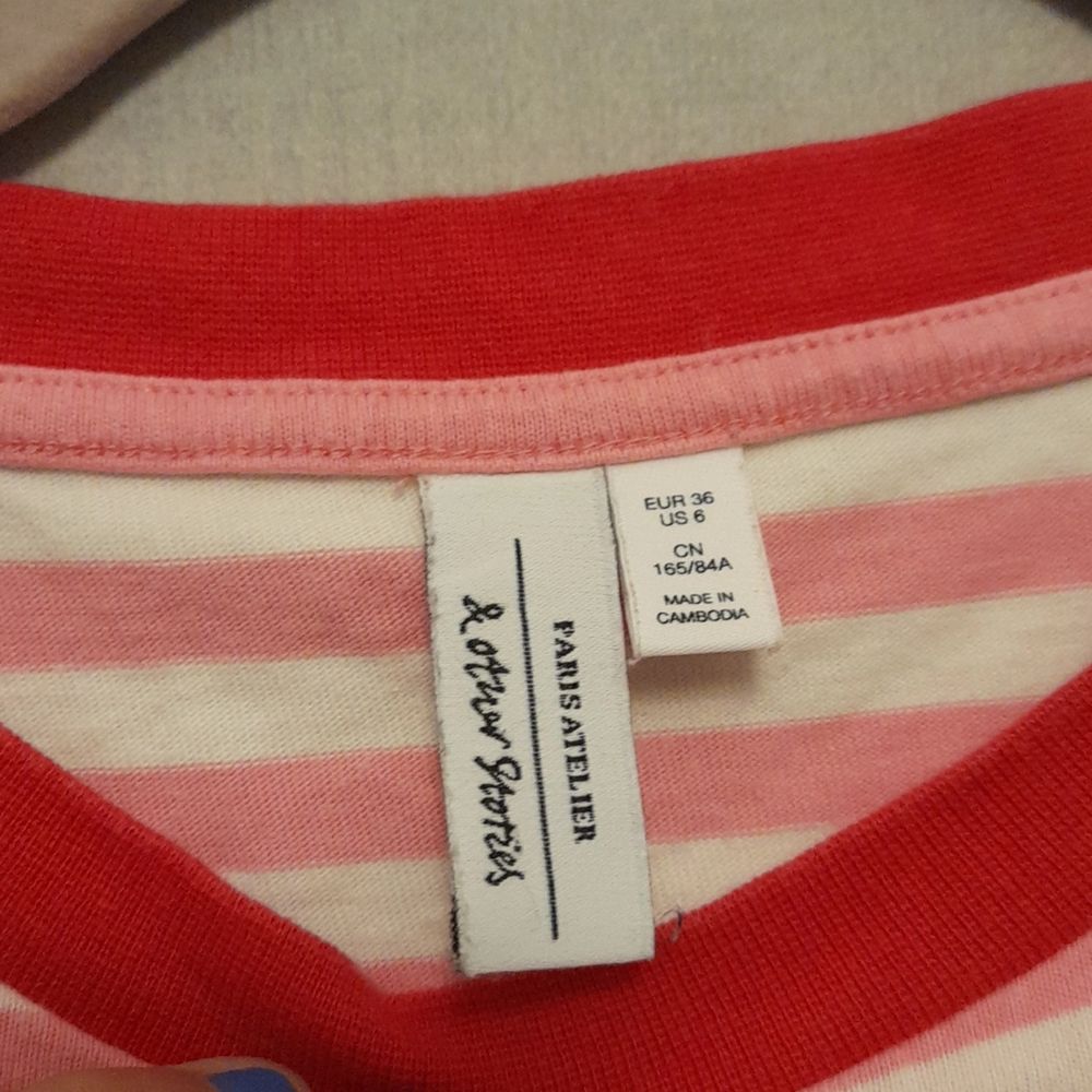 En långärmad tröja med rosa och vita ränder och en röd krage säljs i stlm . Tröjor & Koftor.