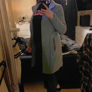 Varm kappa i grått med svarta detaljer  - En varm jättefin kappa använd max 3 gånger. Inköpspris 999 kr. 