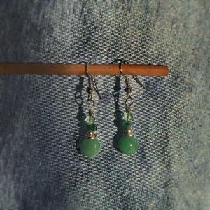 Gröna långa örhängen - Ett par fina långhängande örhängen med gröna stenar/pärlor. Krokarna gjorda nickelfria, handgjorda och helt oanvända. Kan fraktas eller mötas upp i Stockholm/Huddinge. Skriv vid frågor!