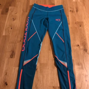 Träningstights Kari Traa - Turkosa/orangea träningstights från Kari Traa. Endast använd ett fåtal gånger, i nyskick! Dragsko i midjan och reflexer på benen, perfekta för löpning. Ficka för nycklar bak. Mer åt det gröna hållet än bilderna visar.