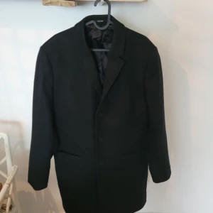 Cempsey rock tiger of sweden - Rock från Tiger Of Sweden i en mjuk kashmirmix. Rocken har två sidofickor, en bröstficka och tre innerfickor. Ärmsluten har fyra knappar och baktill finns ett sprund. Insidan är fodrad i svart satin.  Yttertyg: 30% Polyester, 60% Bomull, 10% KashmirFoder: 100% ViskosKemtvättRocken har använts 2 gånger enbart. Den är i mycket bra skick.  storlek : large , 46-48  , butikspris 3800 kr 