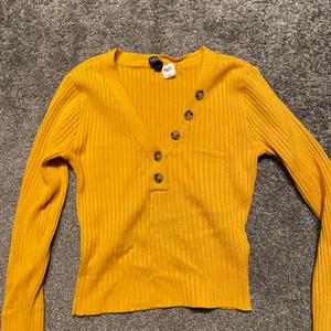 Gul stickad tröja - Tröja från h&m. V ringad med några uppknäppbara knappar längst ner. Knappdetaljer på ärmen. Kolla in min profil säljer massa annat! Om du är intresserad av fler saker kan vi komma överens om ett paketpris☺️