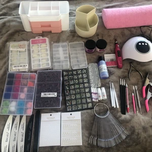 Nagelkit - Helt nya nagel produkter kommer allt som är med på bilderna. fyra pack lösnaglar, akryl färger i vit och rosa + liquid, 6 penslar, uv lampa, borrmaskin, 2 pack kristaller, 5 lim, 5 fil, rosa handstöd, sandpapper till borrmaskin, 2 nagelsax och 2 klistermärken med bokstäver.
