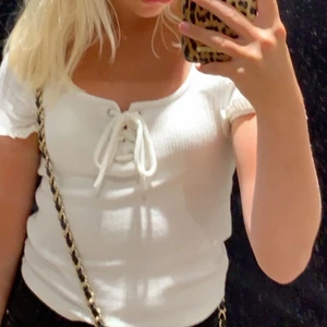 Vit T-shirt  - Söt T-shirt med snörning fram. Lätt ribbat material. Jättefint skick och sitter så bra. Säljer pga för liten på mig. 🤍