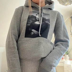 Grå hoodie - Hoodie från The Cool Elephant med tryck på mona lisa. Köpt för 2 år sedan och använd max 2 gånger så den är i nyskick. Köparen står för frakten💓