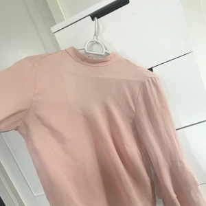 Rosa blus med volang - Rosa blus med volanger på ärmar och knytning bak från Ginatricot. Ursprungspris 399kr, säljes för 75kr. 