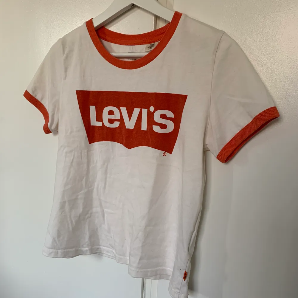 En cool levi’s tröja med oranget tryck och oranget vid kragen och armarna. Väldigt bra skick och sällan använd.. T-shirts.