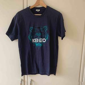 Cirka 3 år gammal mörkblå t-shirt från Kenzo i storlek M, köpt på Kenzos hemsida. Har ett litet hål nere vid kanten och därmed kan priset diskuteras.