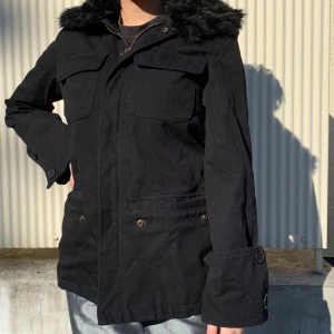 Jacka med krage i faux fur - En elegant jacka med krage i faux fur. Vida ärmar och stora knappar. 