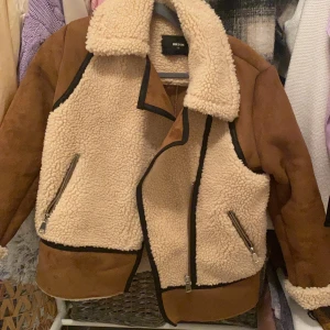 Jacka - Säljer en jacka med brun, beige färg och svarta detaljer. Knappt använd och säljer då den inte kommer till användning, då den är lite oversized passar den även bra till S😊