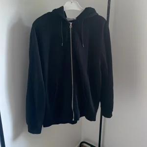 Svart zip hoddie i storlek M - Tröjan är svart och är köpt på weekday för 400kr. Knappt använd och är i mycket bra skick (inga skador)