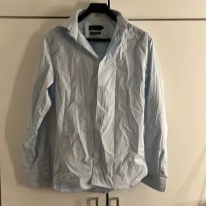 Blå skjorta  - En ljus blå skjorta som är använd på gånger och är i ett väldigt bra skick. 