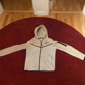 Beige Nike tech fleece - Använd fåtal gånger. Inprincip helt ny, skick 10/10. Inget är sönder. Storlek S men sitter som M. Ordinarie pris 1200kr. Pris kan diskuteras.