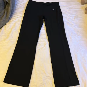 Lågmidjade bootcut nike tights - Lågmidjade svarta träningsbyxor i tightsmaterial från Nike, som är utsvängda och har inga märkvärdiga tecken på användning