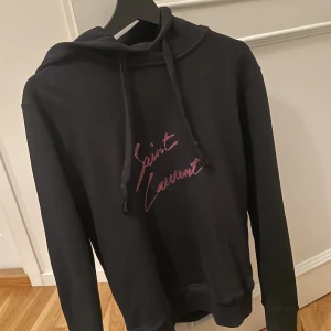 Saint Laurent Hoodie (Unisex)  - Unisex Saint Laurent Hoodie köpt från Haiendo. Ordebekräftelse och tags finns till tröjan. Storlek XS men passar även en S herr. ENDAST ANVÄND VID 2 TILLFÄLLEN DÄRAV I NYSKICK! 