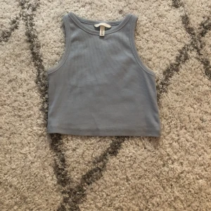 Croppat ljusblå linne - Ett jättefint croppat linne från H&M, ljusblått och ribbat använt två gånger och inga defekter💙💙