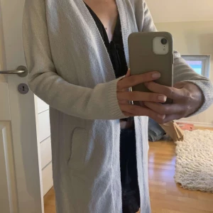 Grå kofta  - En lång stickad kofta i ljusgrå. I bra skick knappt använd. Storlek: 158 