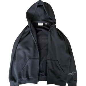 Fear of God Essentials zip hoodie  - Säljer min essentials hoodie, då den inte kommer så mycket till andvänding. Fint, men använt skick. Stor i storlek, så om du är vanligtvis M kommer den passa dig. Hör av dig om du har frågor eller eller vill ha fler bilder.