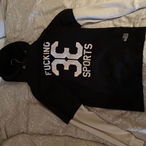 H&M hoodie svart/vit. - En Hoodie från H&M som jag vuxit ur.  Stilren och cool. Svart med vita armar. Bra skick, lite sliten på ”33” trycket men fortfarande riktigt snygg. Skick 7/10